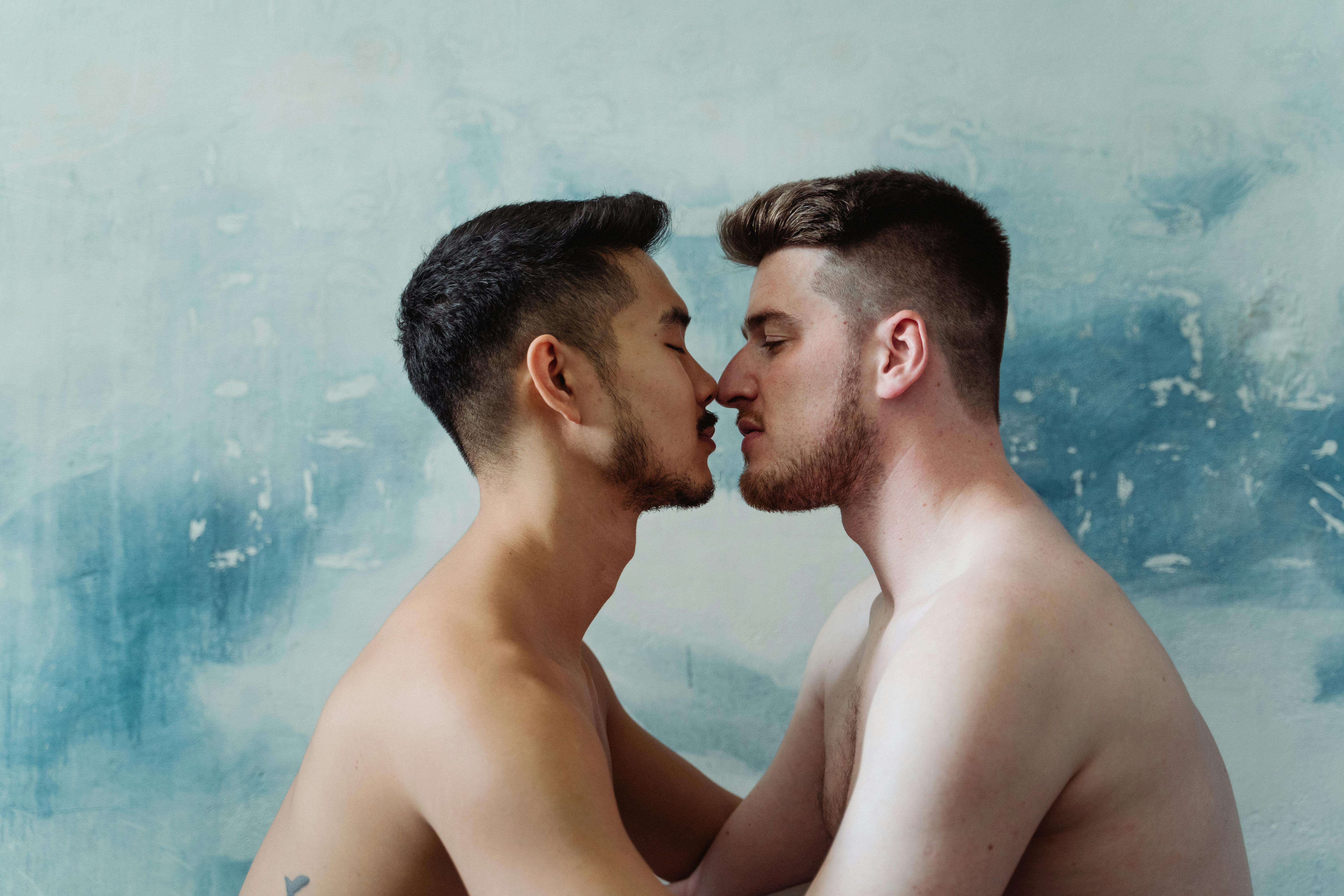 two shirtless men about to kiss
