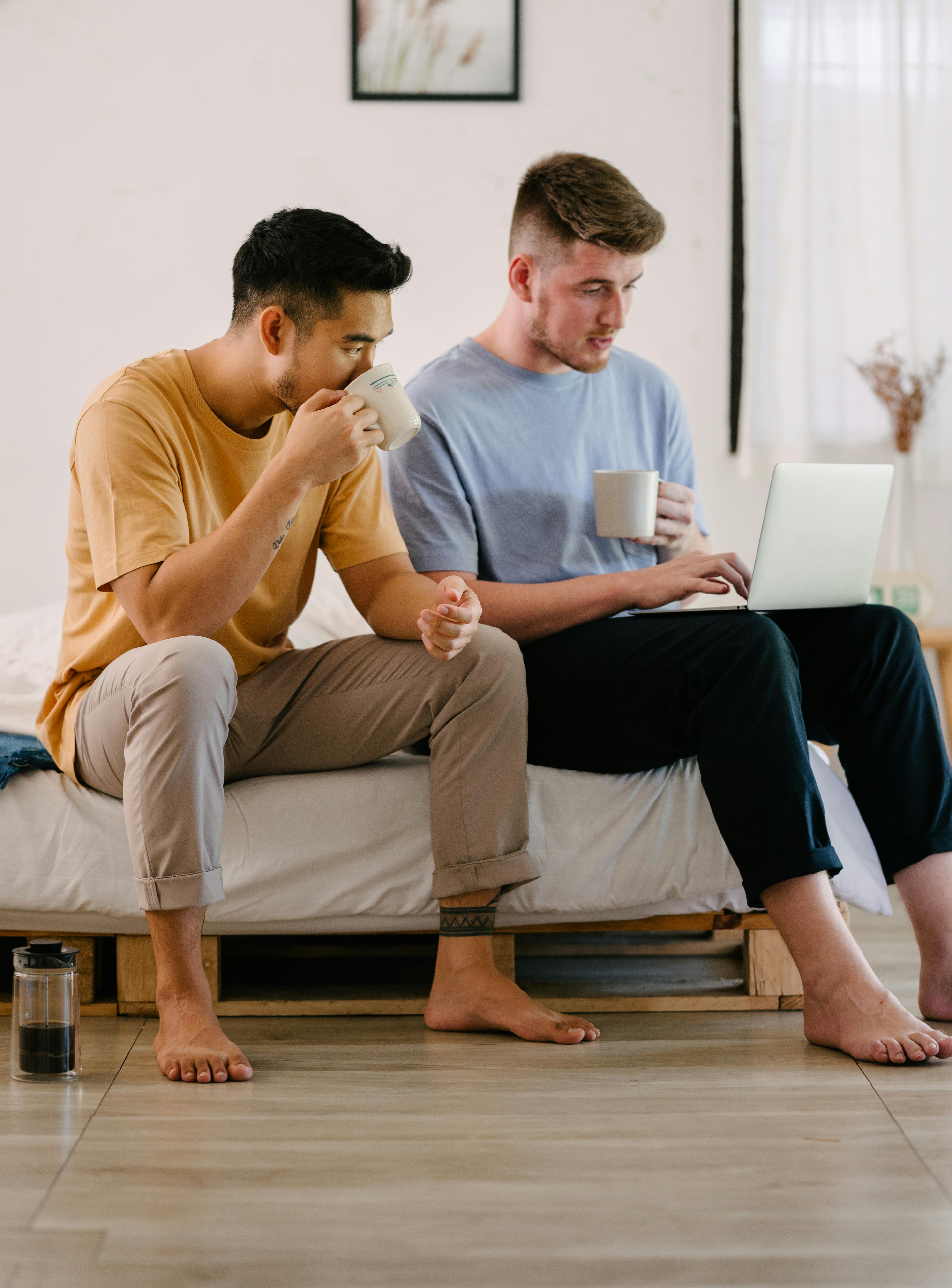 a couple looking at a laptop sitting with cups of drink