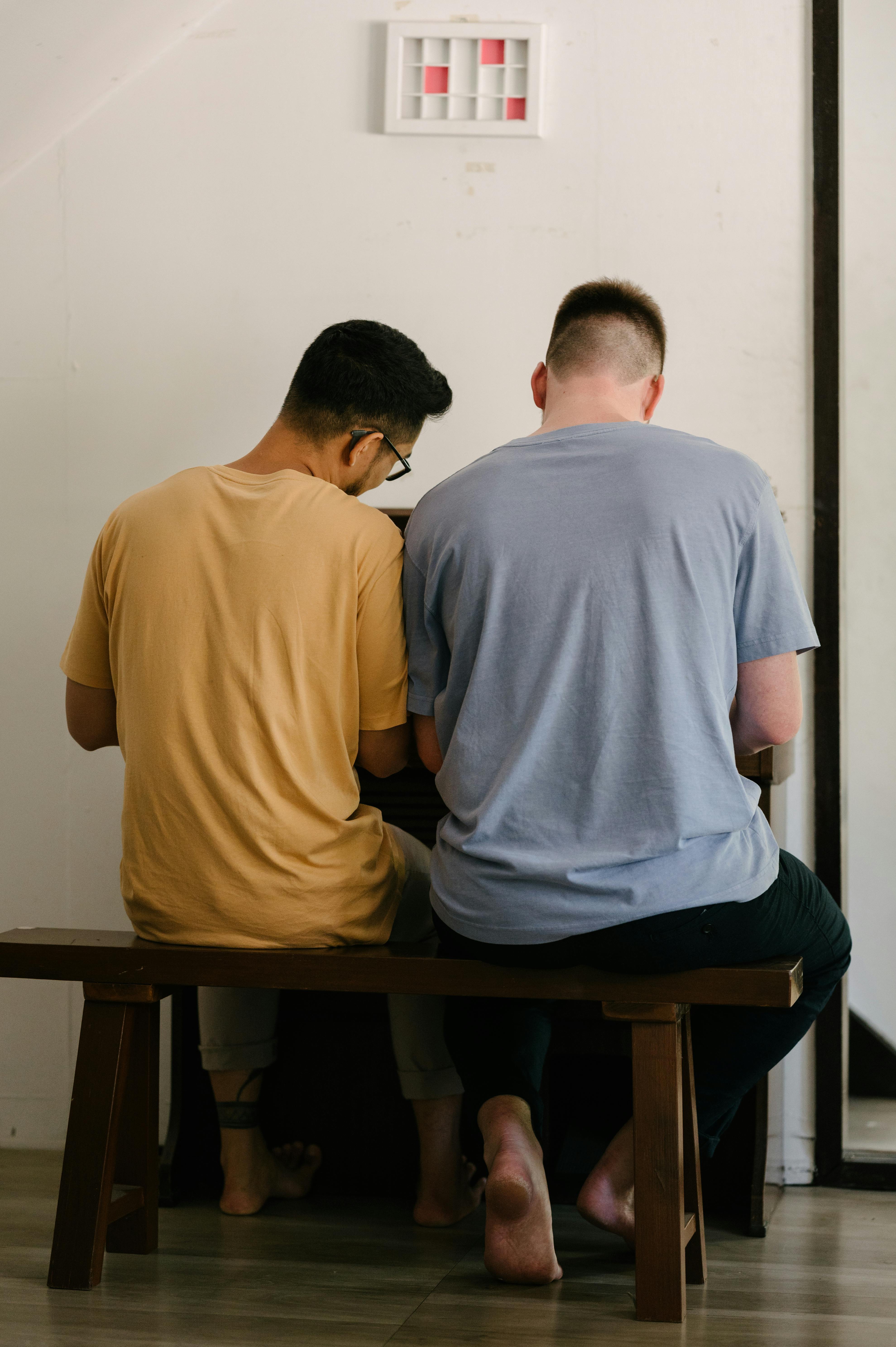 两个男人并排坐在室内弹钢琴，营造出团聚的氛围