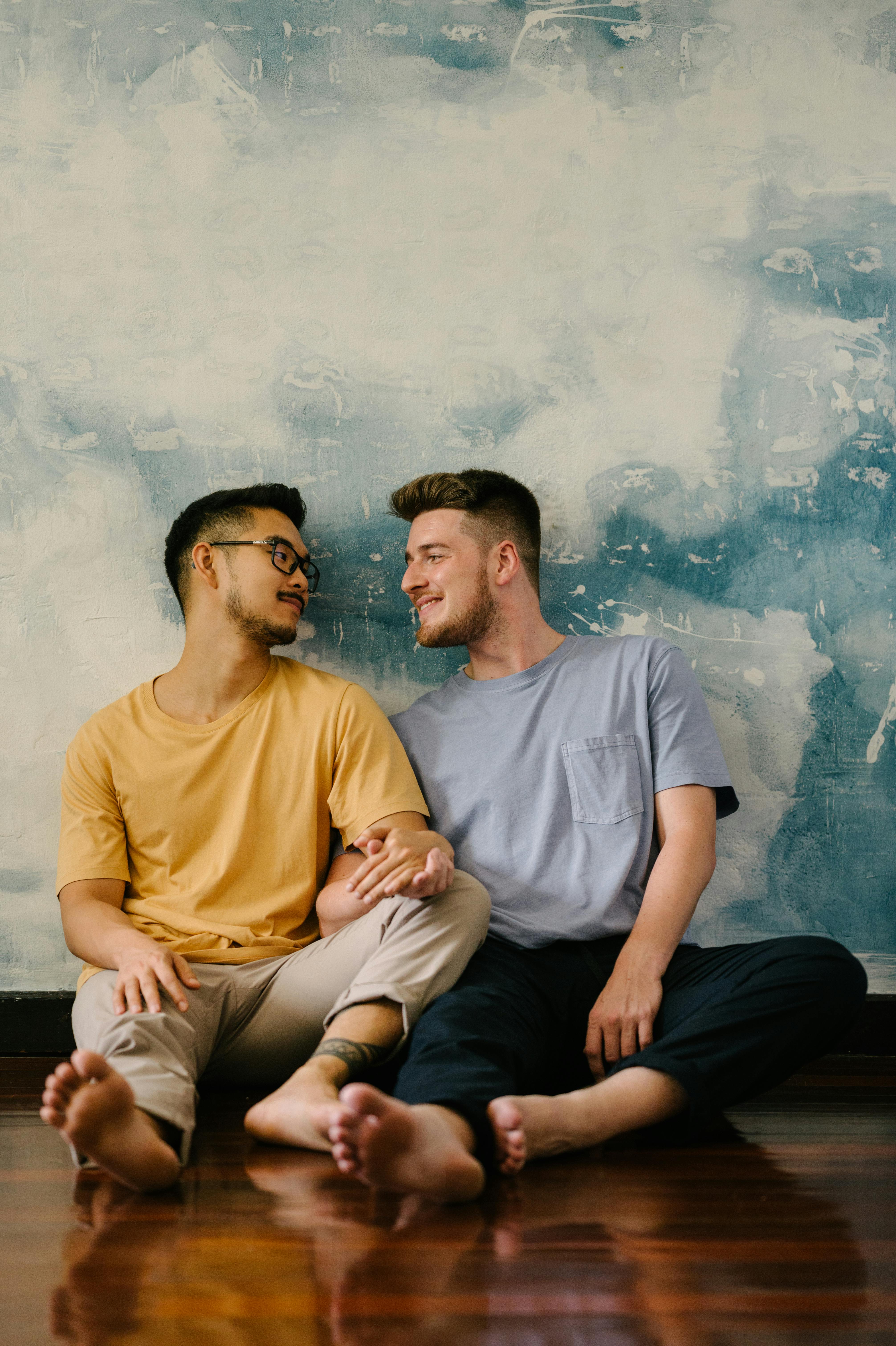 two men sitting on the floor and holding hands