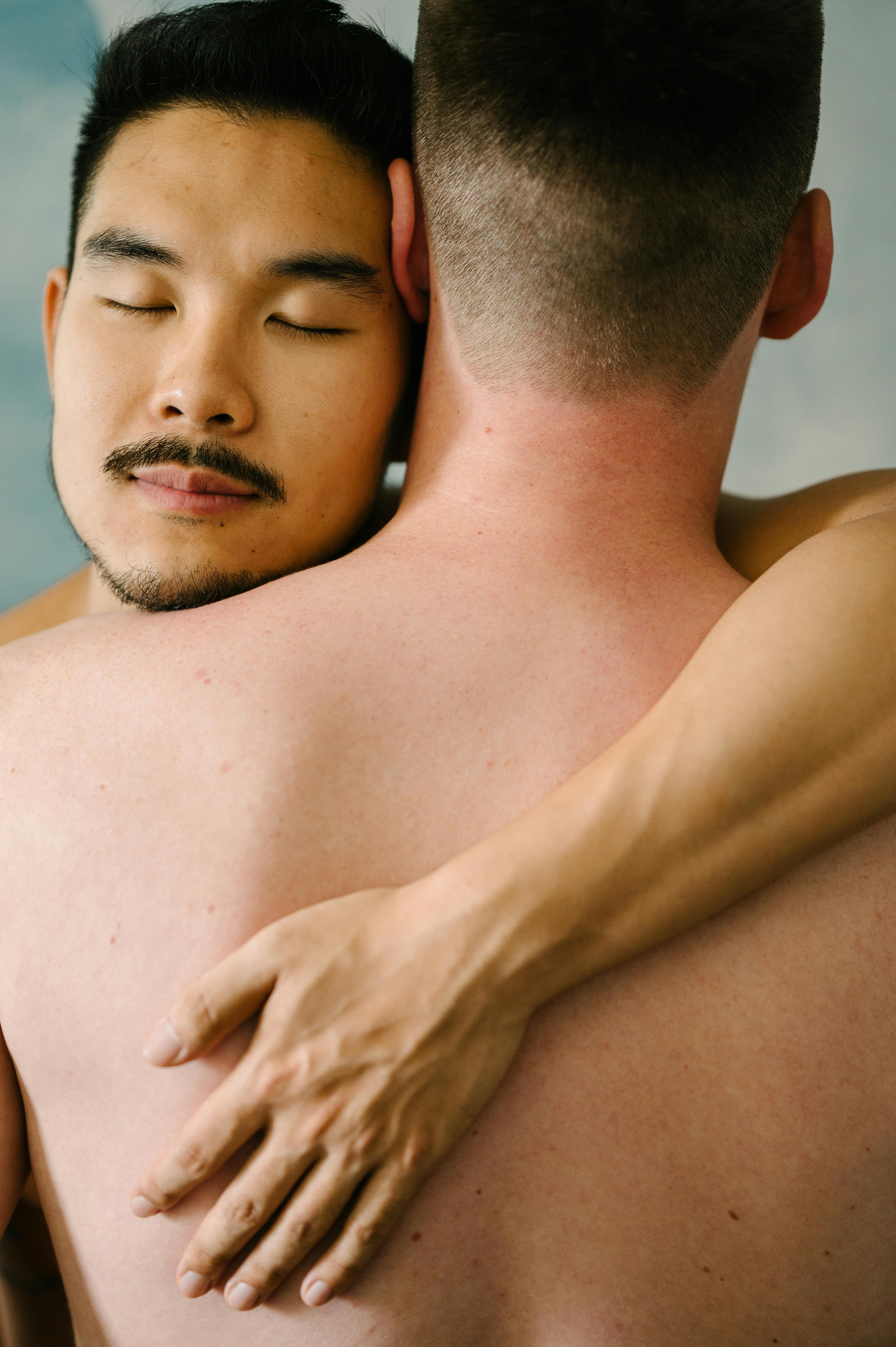 two topless men hugging