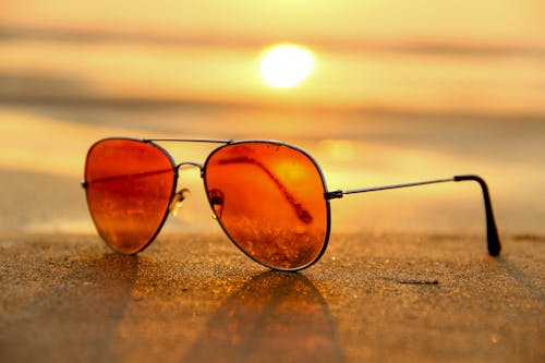 Rote Linsen Sonnenbrille Auf Sand In Der Nähe Des Meeres Bei Selektiver Fokusfotografie Bei Sonnenuntergang