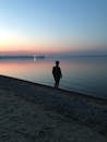 Silhouette of a Person Standing by the Seashore