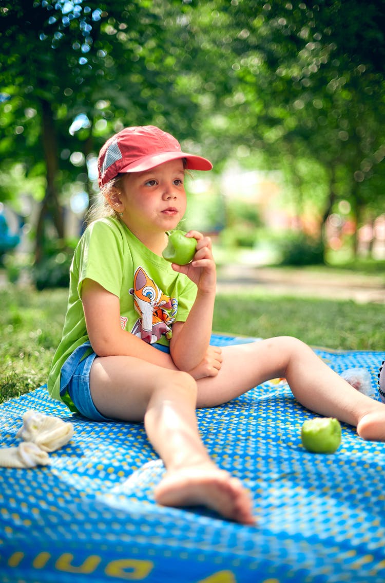 Girl Eating An Apple Sitting On The Park