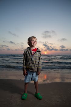 A young boy enjoying a peaceful beach sunset, perfect for family and lifestyle themes.