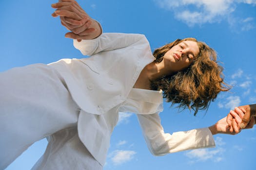 一名女子身穿白色西装，在充满活力的蓝天下优雅地摆出姿势