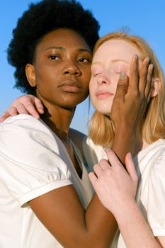 两位多元化的年轻女性在清澈的蓝天下相拥，象征着姐妹情谊与团结