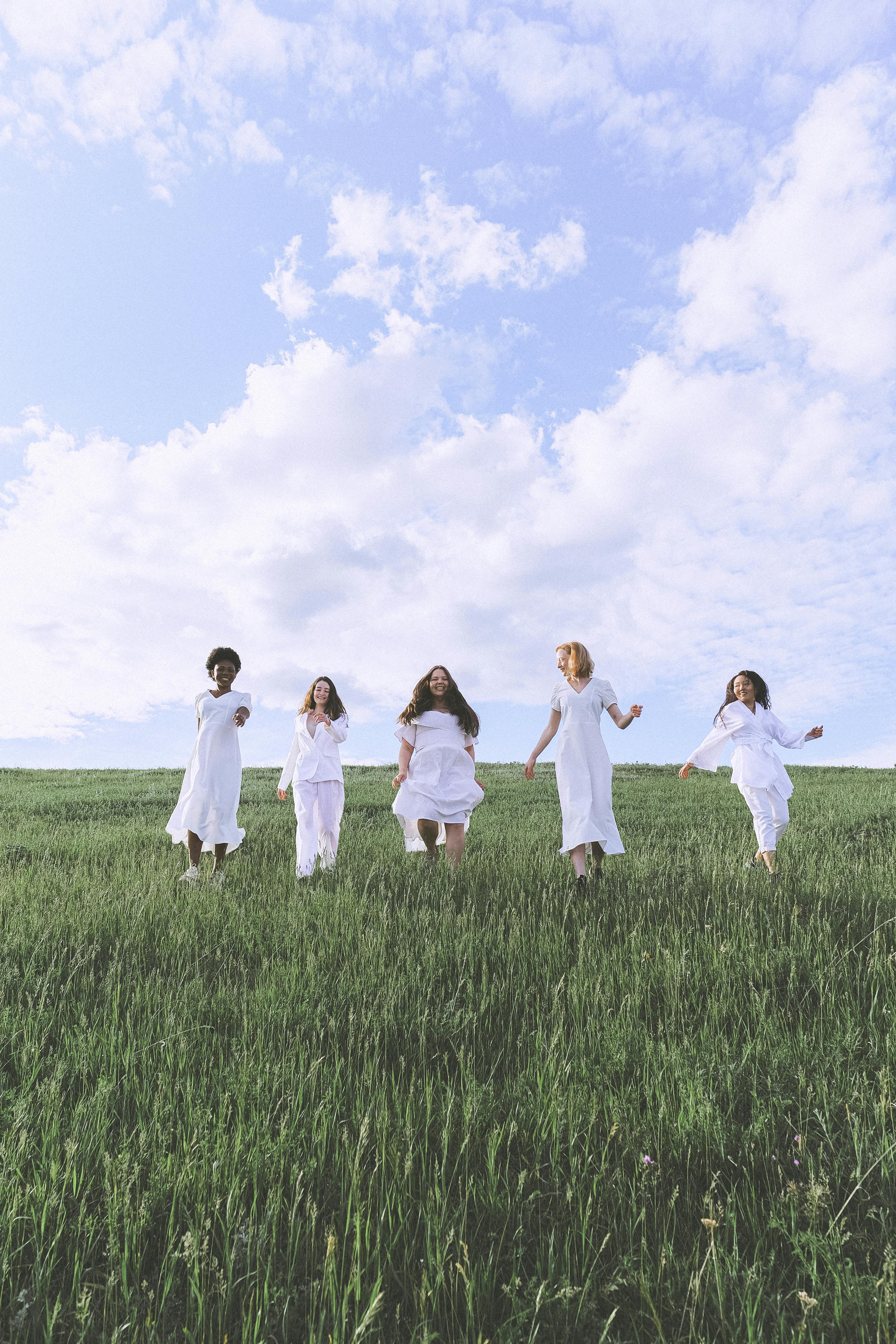 group of people standing on green grass field under blue sky