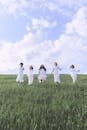 Group of People Standing on Green Grass Field Under Blue Sky