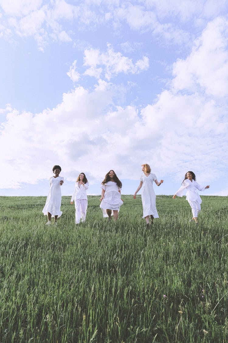 Group Of People Standing On Green Grass Field Under Blue Sky