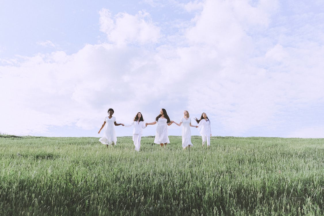 Group of Women Walking on a Grass Field