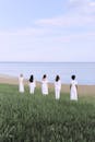 阳光明媚的夏日，五名身穿白色连衣裙的妇女面朝大海，象征着团结与和平