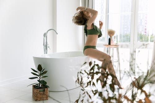 Woman in GreenSexy Wear Sitting On Bathtub