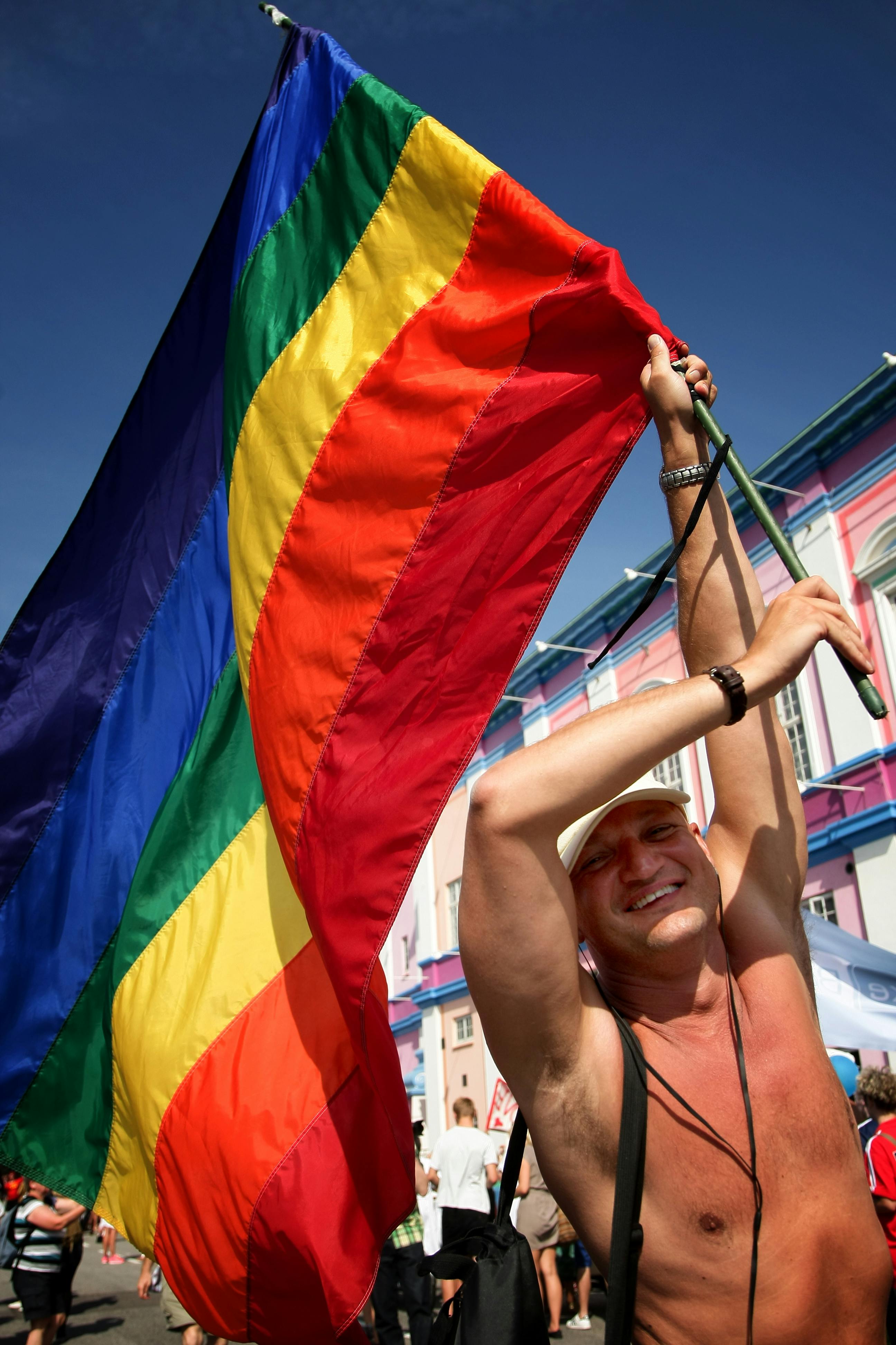 shirtless man holding a colorful flag