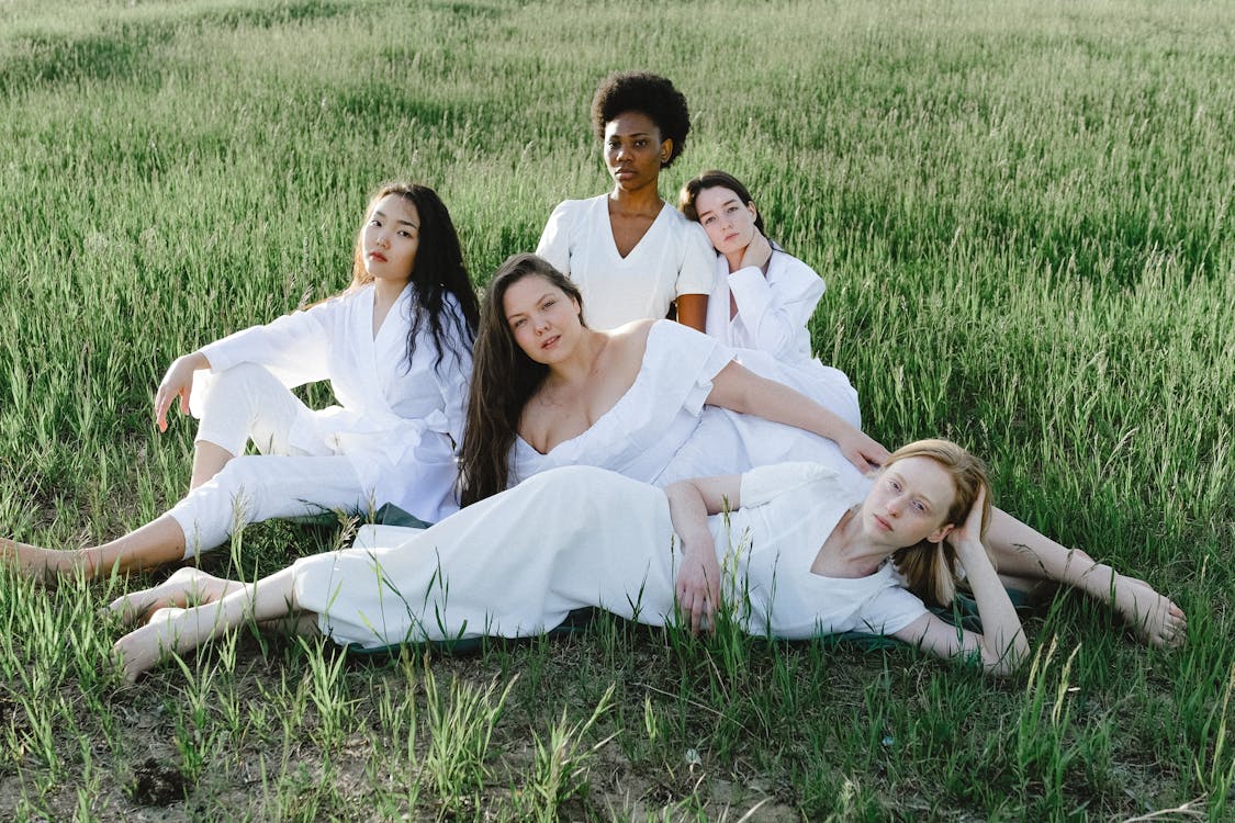 Free Group Of Women Lying On Green Grass Field Stock Photo