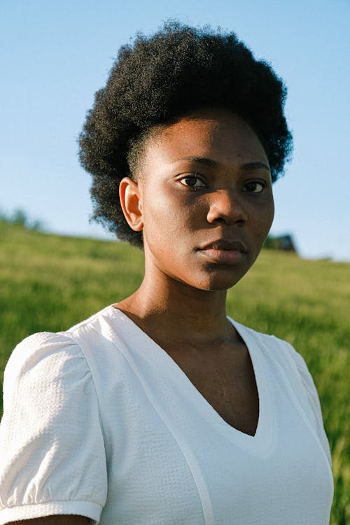 natural hairstyles for work: Woman in White Crew Neck Shirt Standing on Green Grass Field