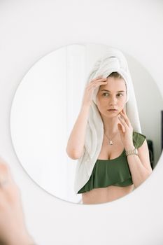 年轻女子裹着毛巾，看着室内的镜子