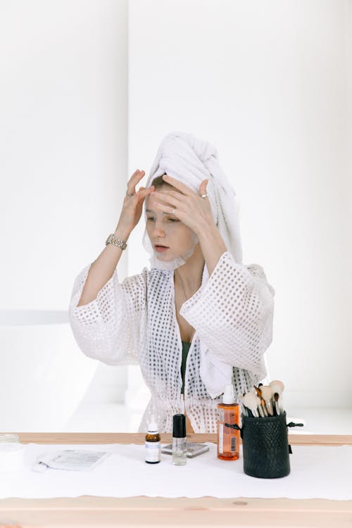 Photo Of Woman Putting Facial Mask On Her Face