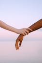 特写镜头中，两只肤色不同的手轻轻握住宁静的日落天空