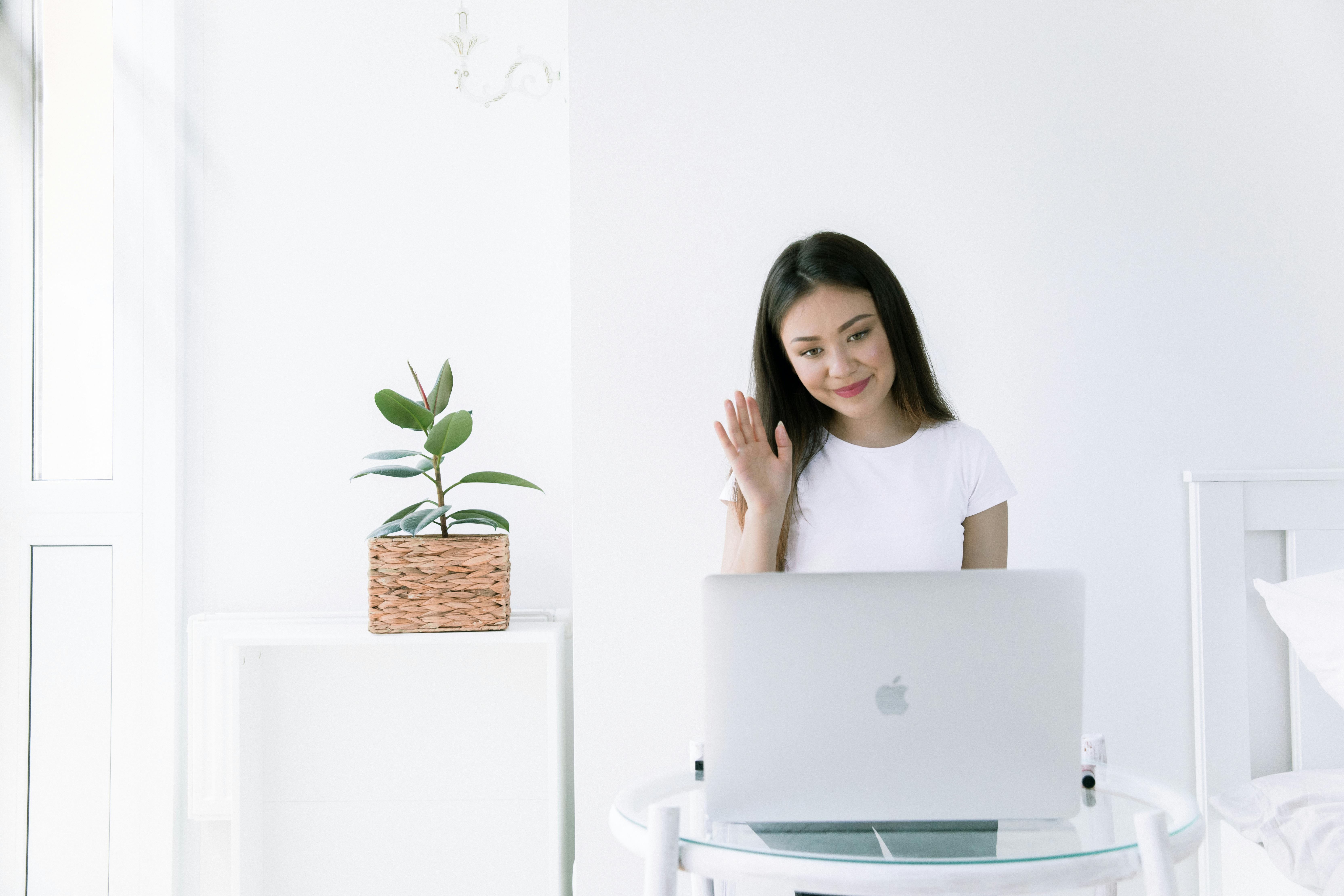 photo of woman waving at laptop