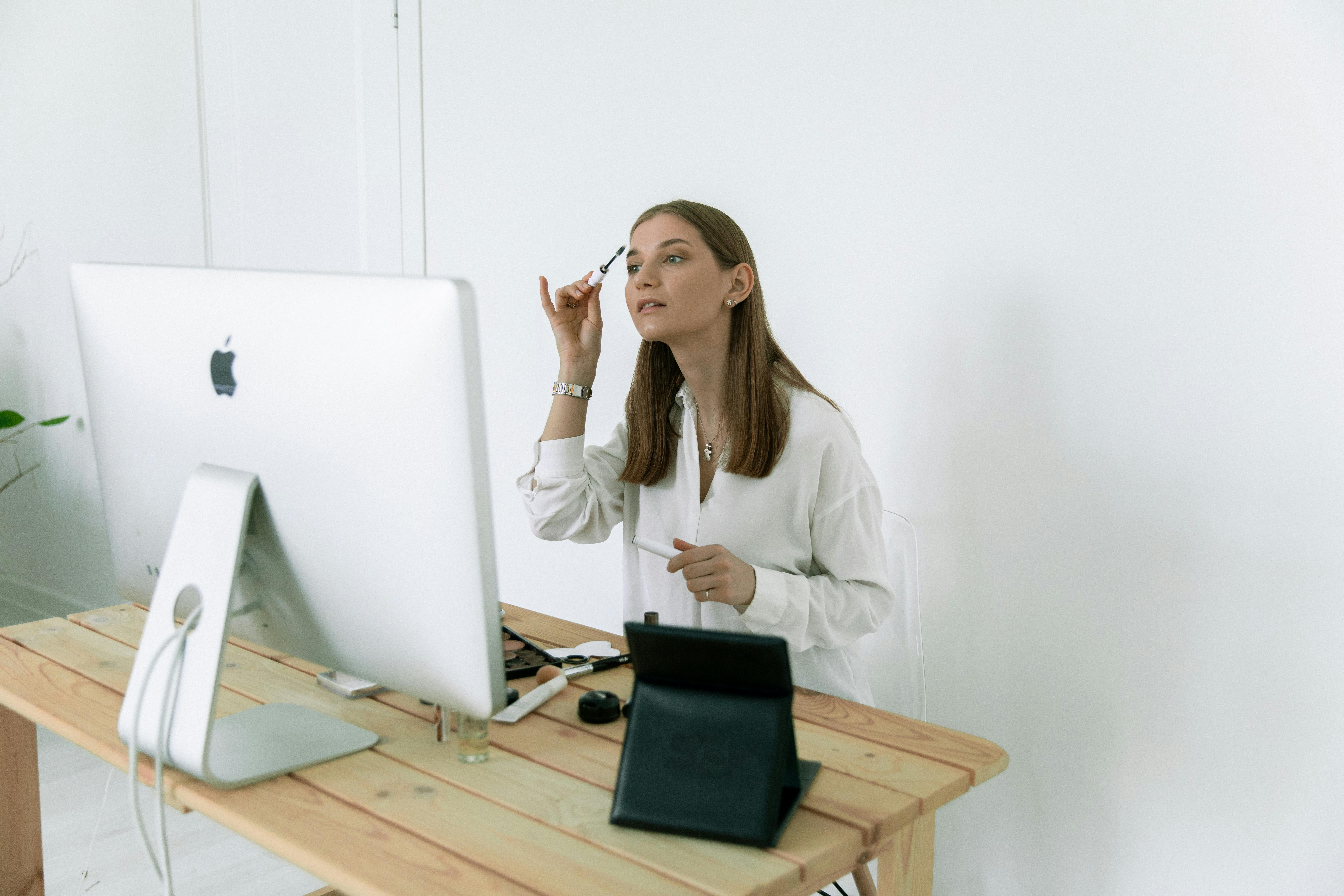Person applying makeup at a desk in an office-like setup