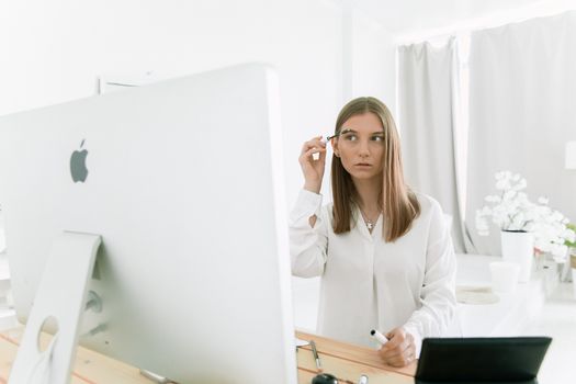 女人在电脑前化妆，将科技与自我护理融为一体