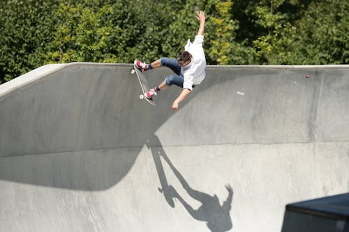 Man in White T-shirt and Black Pants Riding Skateboard
