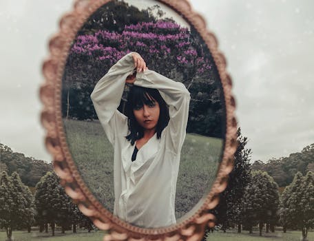 一名女子在户外凝视着一面老式镜子，在大自然中创造了一件反光的艺术作品