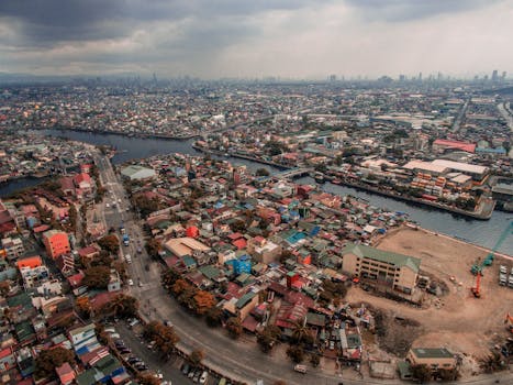 Drone shot capturing the sprawling urban landscape of a Philippine city with roads, buildings, and a river.