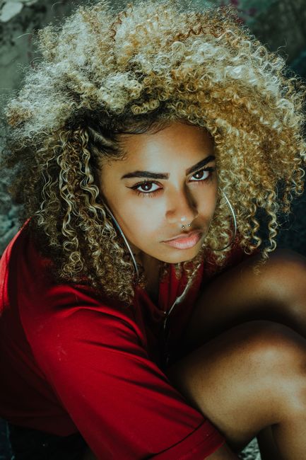 Fashionable woman with curly hair and earrings, captured in an intense and stylish pose.