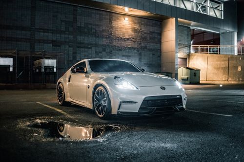 Free White sports car parked in a cityscape at night with glowing reflections. Stock Photo