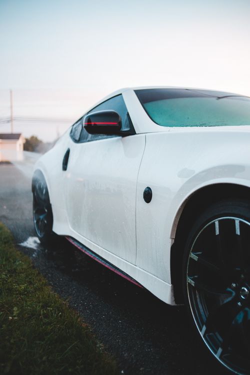 Free Sleek white sports car with modern design parked on a wet pavement, showcasing luxury and style. Stock Photo