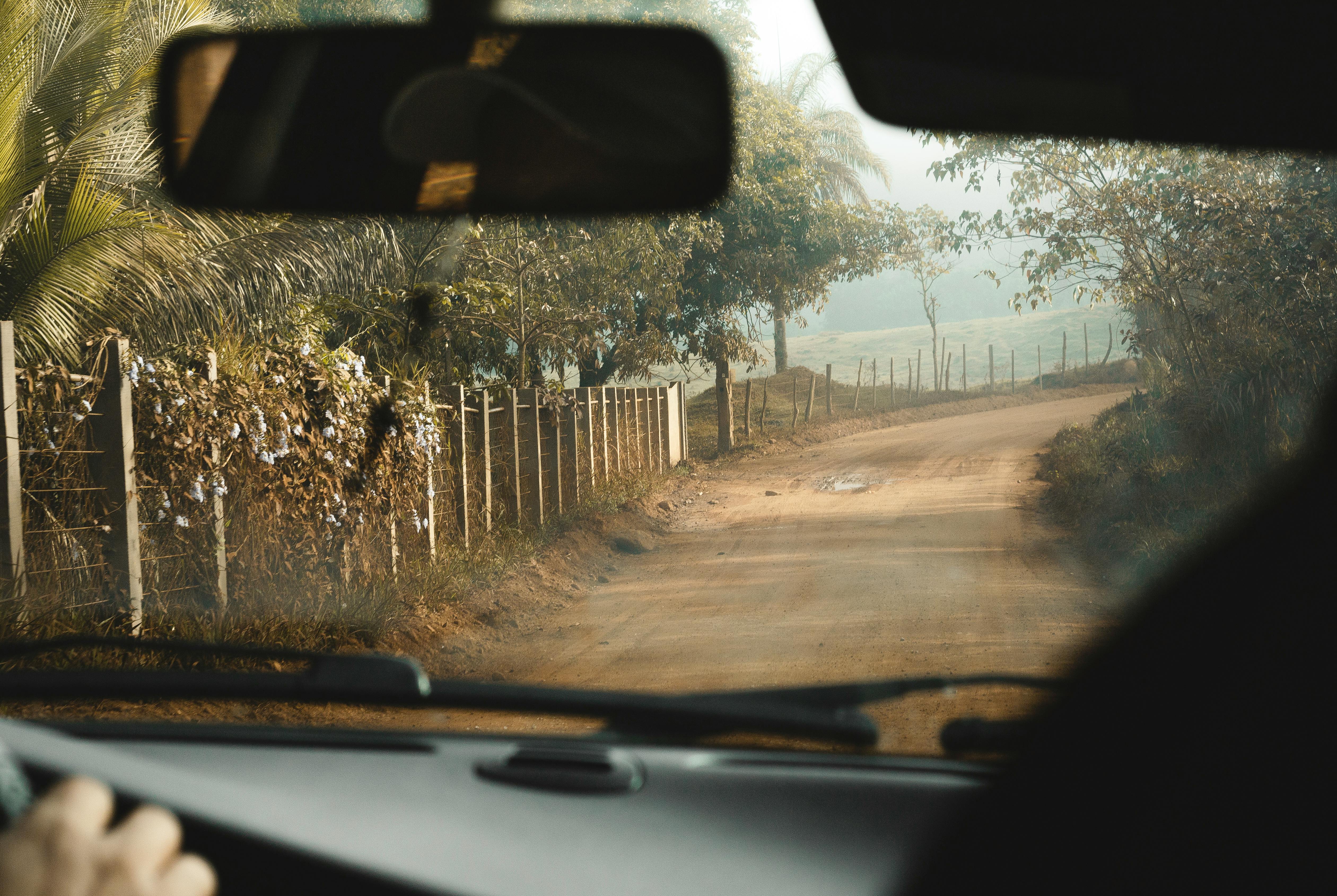 Explore a peaceful unpaved road in Brazil through a car windshield, showcasing nature's beauty.