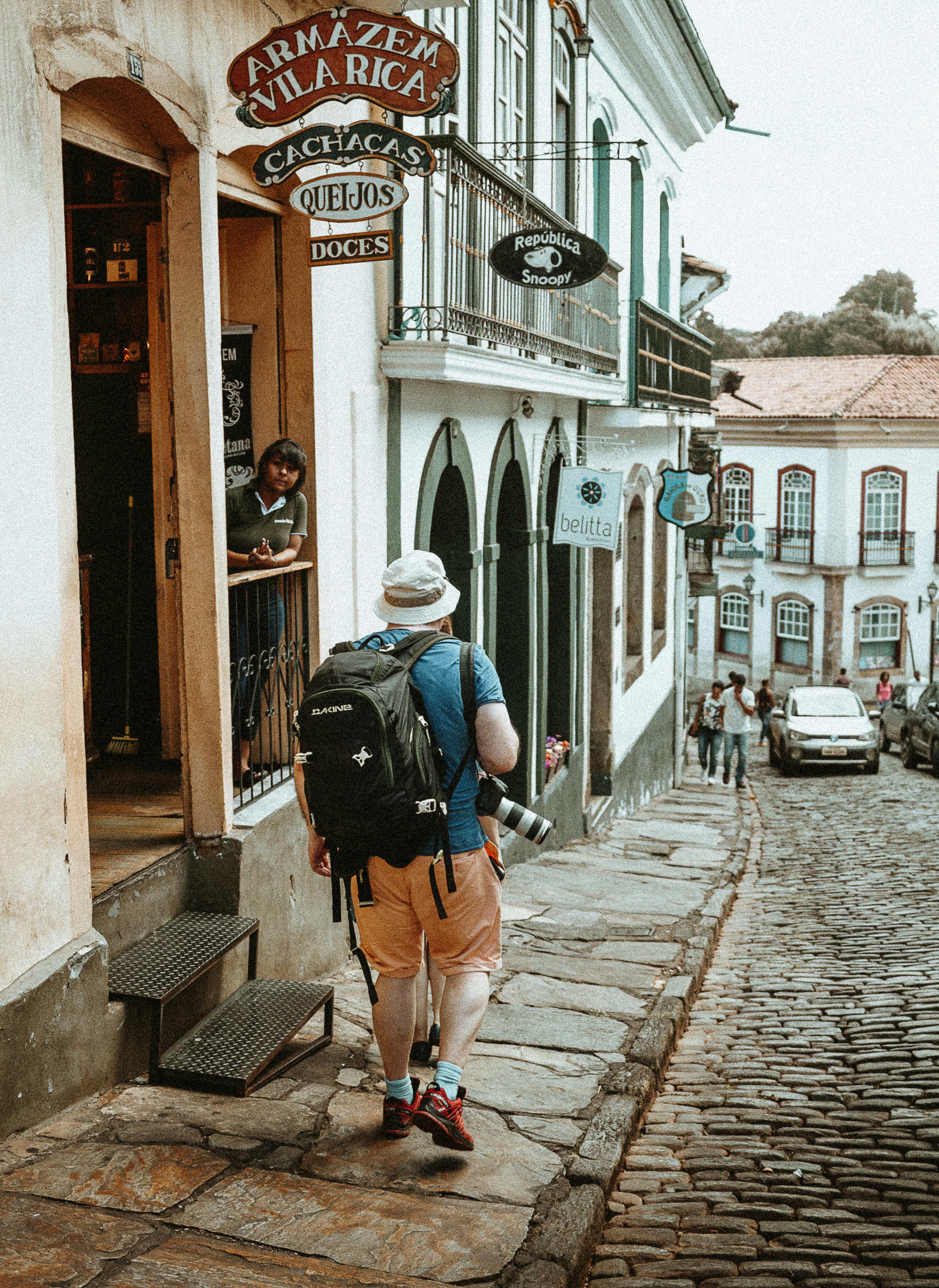Free Man Carrying Backpack Walking on Sidewalk Stock Photo