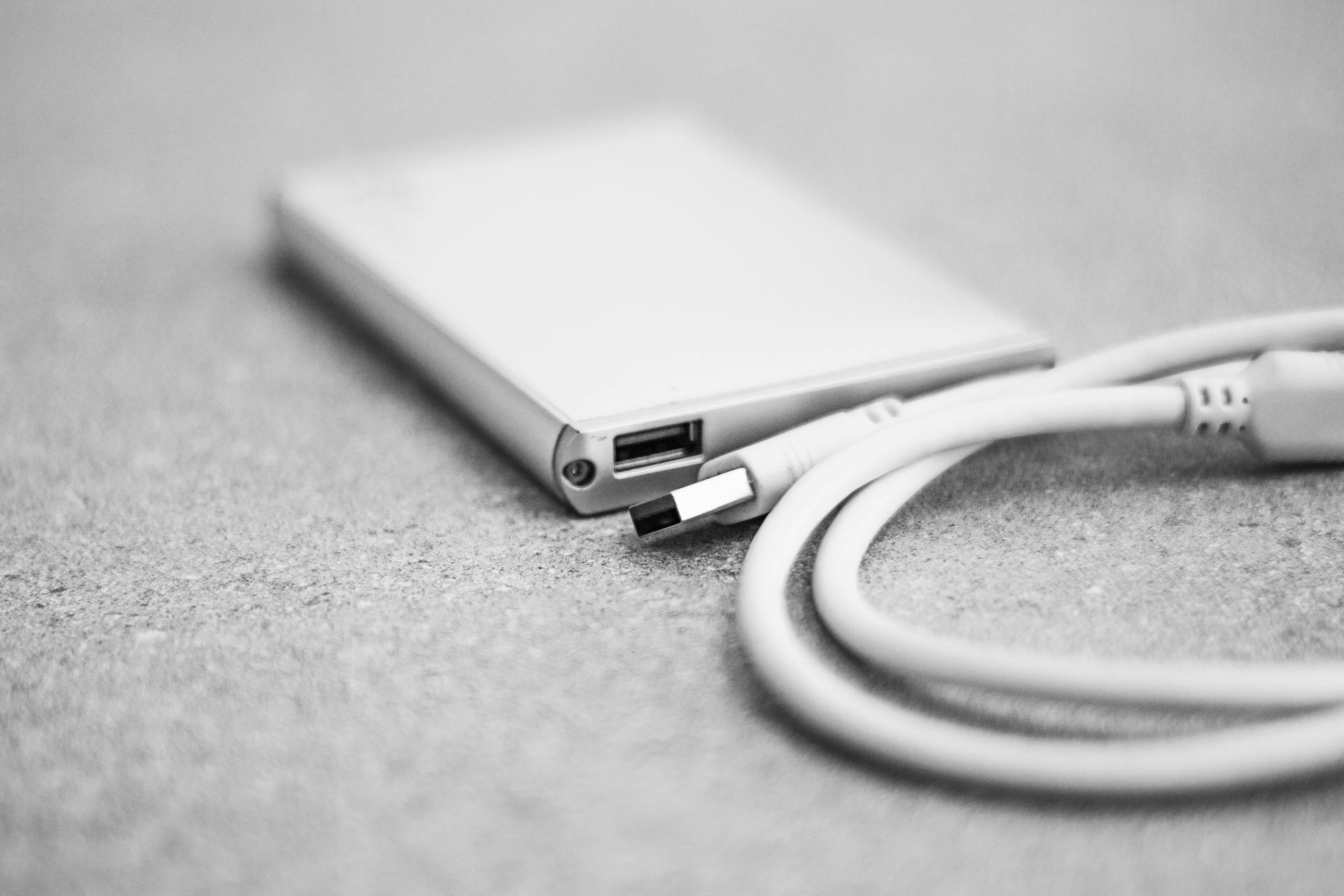 Monochromatic close-up of an external hard drive with a USB cable.