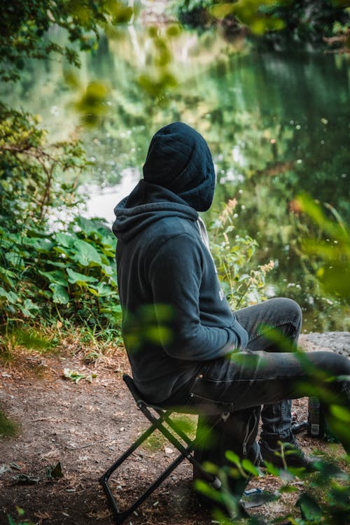 Man in Black Hoodie Sitting on Black Chair
