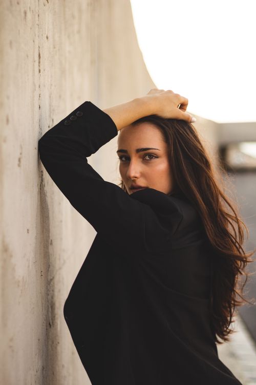 Free Elegant woman poses with confidence and style against a modern concrete backdrop. Stock Photo