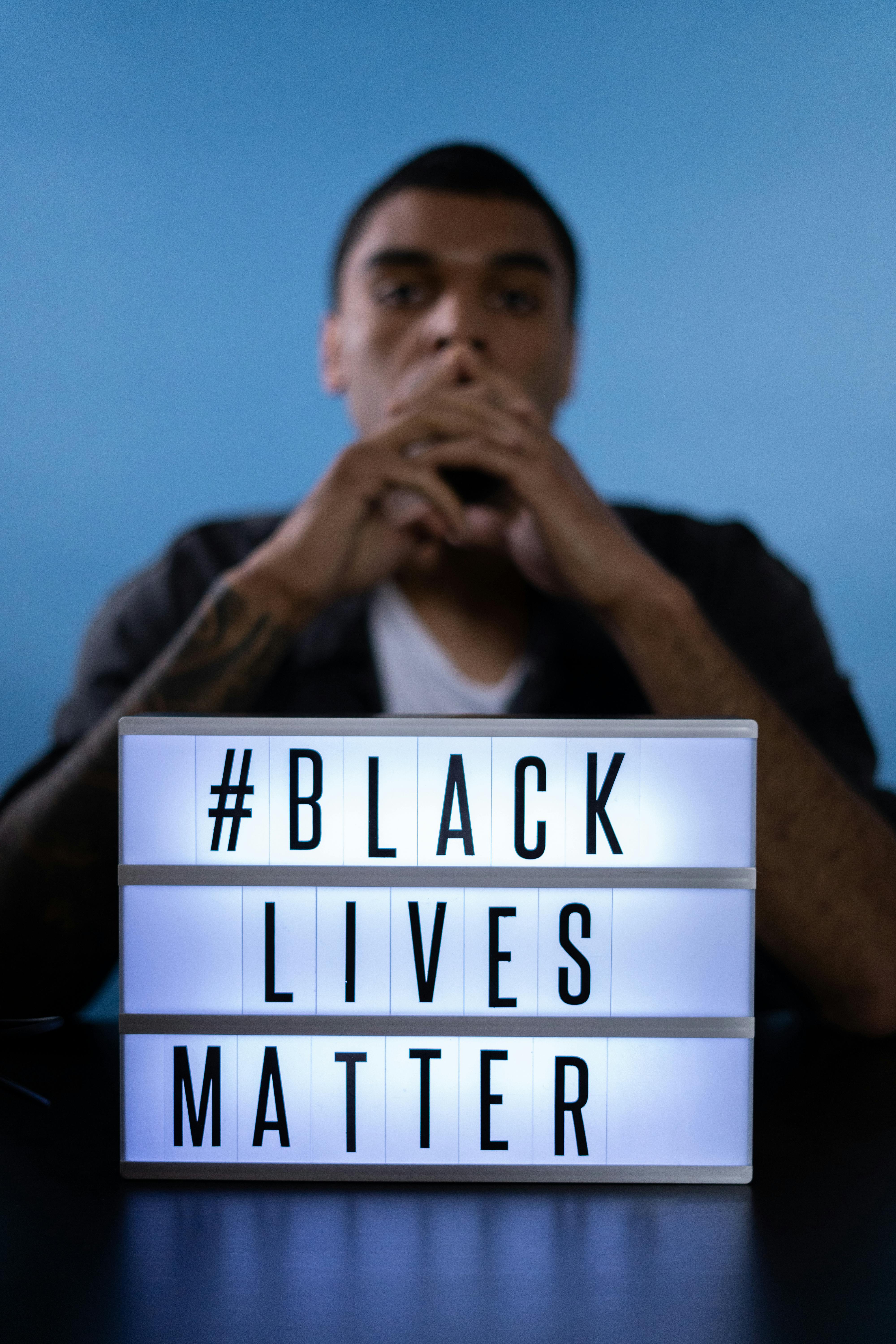 Portrait of a person behind a Black Lives Matter sign emphasizing social justice.
