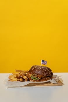 A mouth-watering burger with fries on a vibrant yellow background, perfect for food lovers.