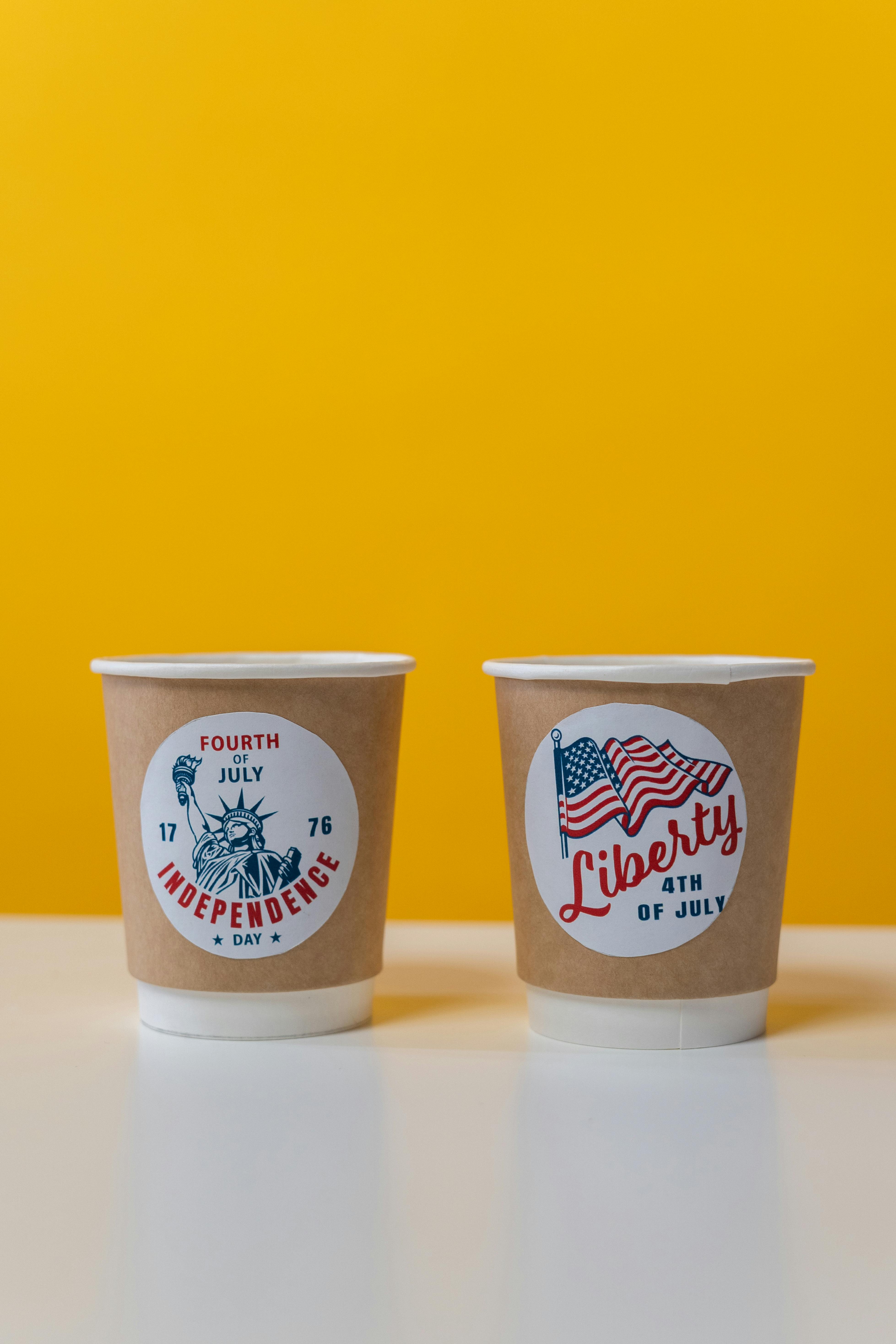 一次性杯子上印有国庆日图案，黄色背景上绘有自由女神像和美国国旗