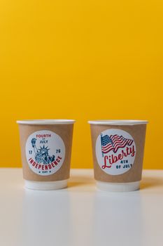 一次性杯子上印有国庆日图案，黄色背景上绘有自由女神像和美国国旗