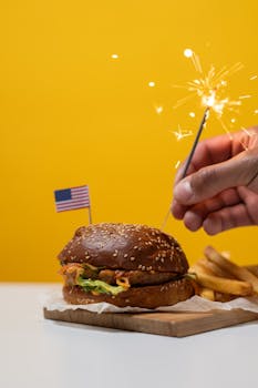 Juicy hamburger with sparkler and American flag, perfect for Independence Day celebrations.