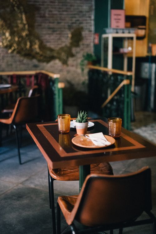 Free Warm and inviting restaurant interior featuring a rustic wooden table set for two with ambient lighting. Stock Photo