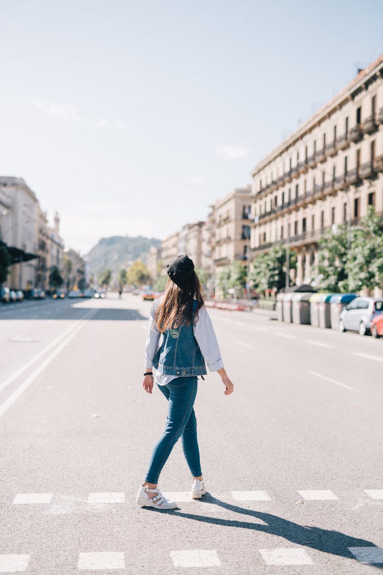 Woman In Blue Denim Jacket And Blue Denim Jeans Crossing The Street