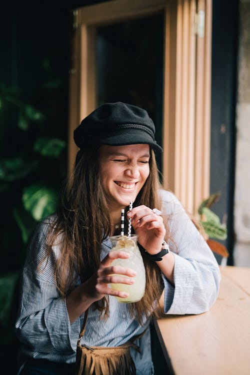 Donna Con Il Cappello Nero Che Beve Il Succo Di Frutta