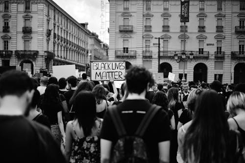 Grayscale Photo of People Rallying on Street