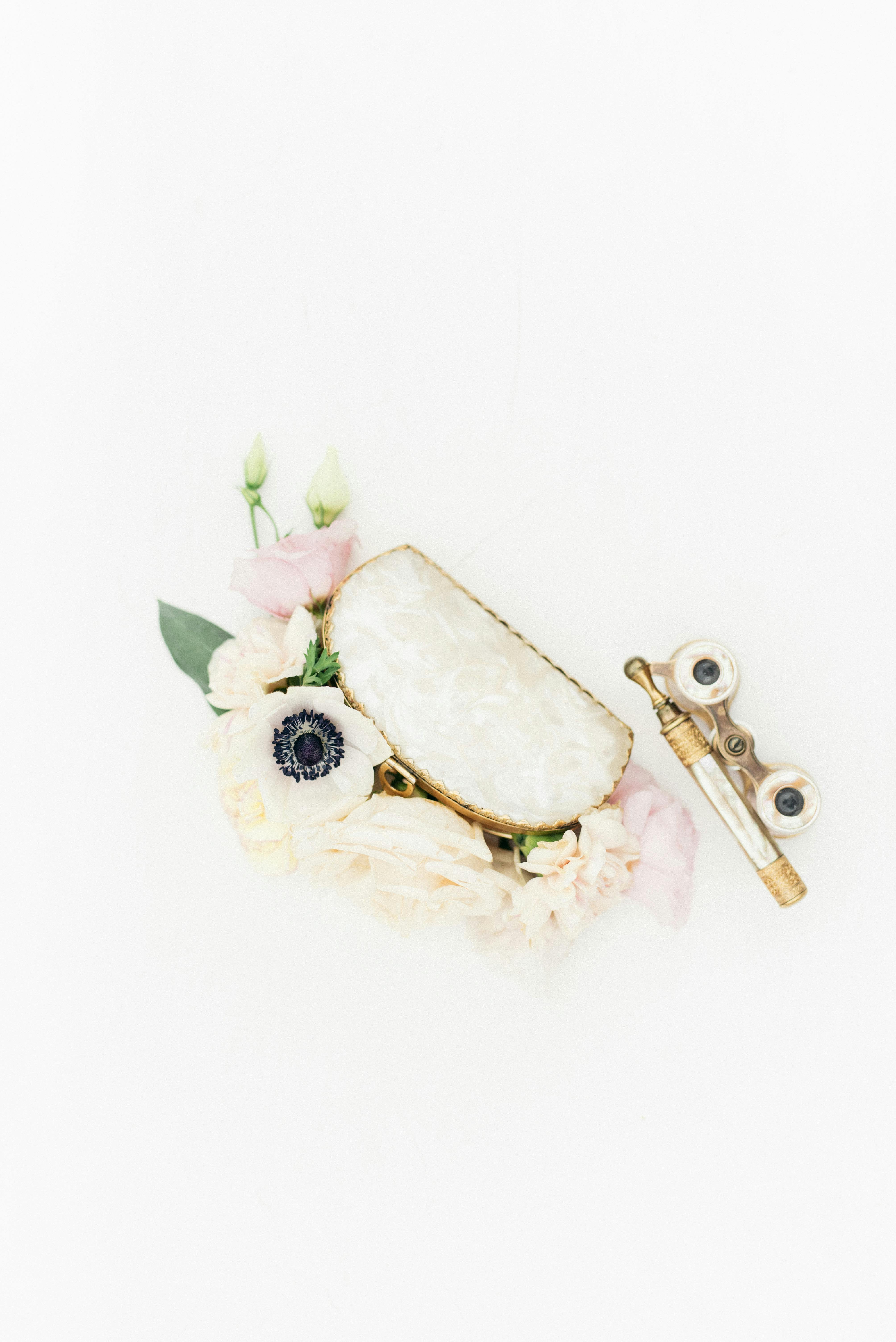 Top view of delicate flowers with vintage binoculars on a white background.