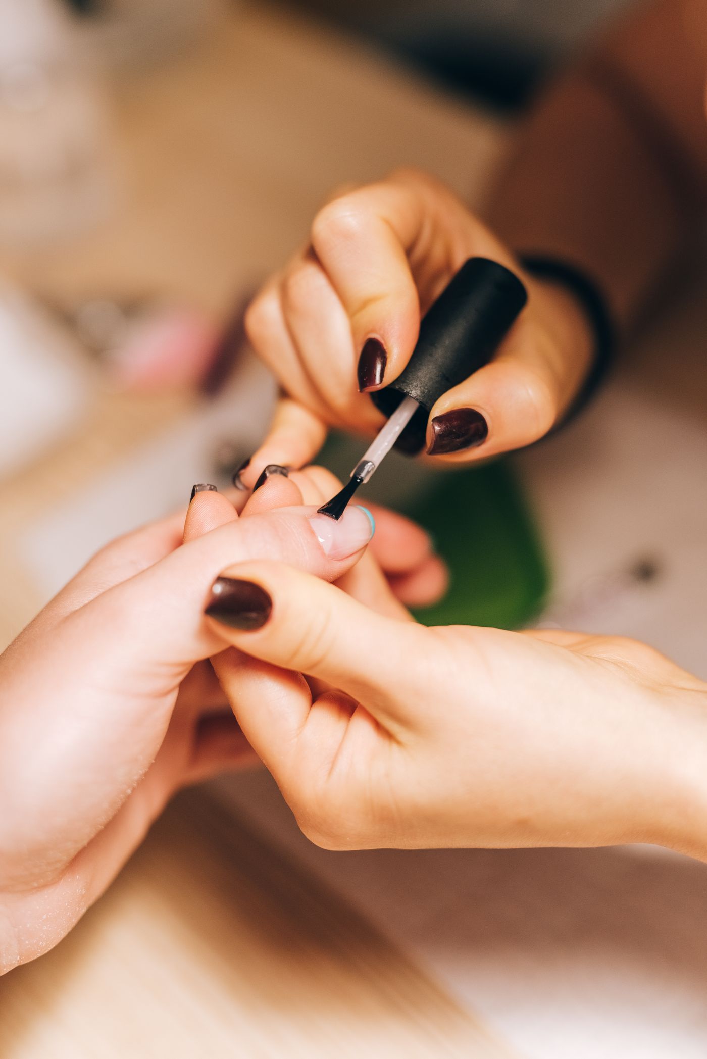 Manicurista aplicando esmalte con pincel a una clienta en el estudio