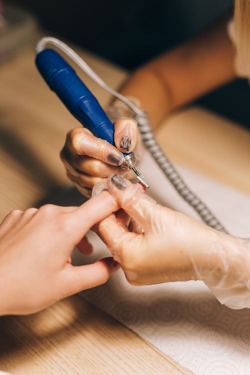 Free Close-up of a nail technician using an electric file during a manicure session. Ideal for beauty and fashion content. Stock Photo