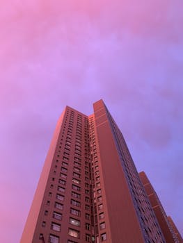 Low angle view of high-rise building against a pastel pink sky.